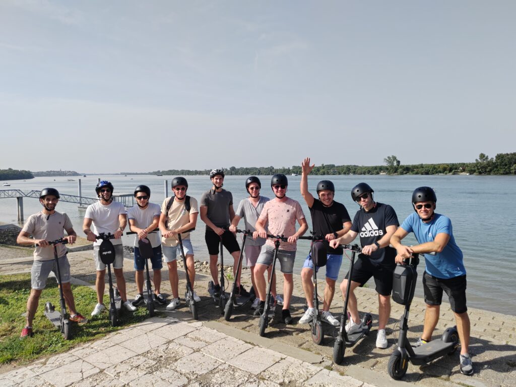 Tourists wearing helmets riding electric scooters through Belgrade during an Electric Scooter Tour