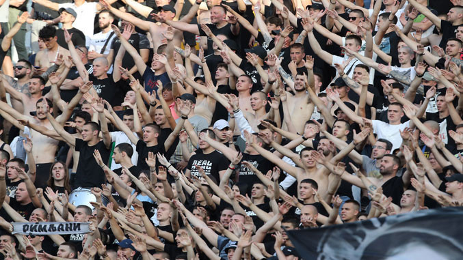Partizan Belgrade supporters cheering on the stadium stands with flags and scarves